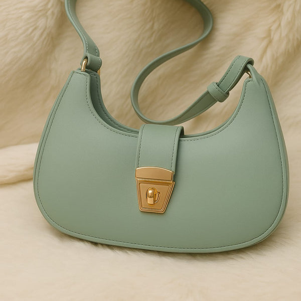 Green handbag with a gold clasp on a beige surface